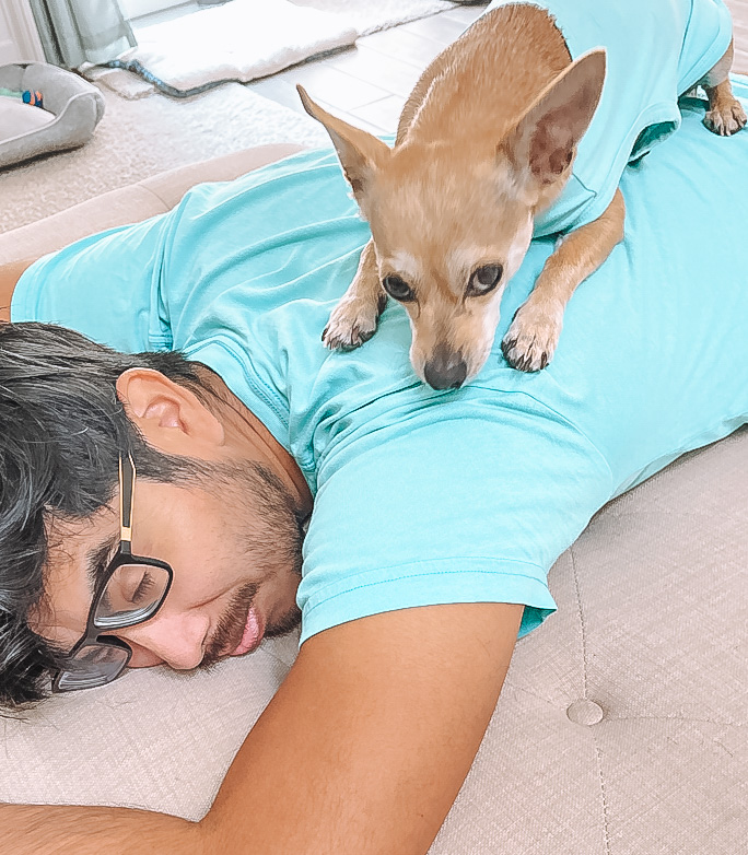 a tan chihuahua is wearing a teal shirt and is laying on top of a man's back wearing a matching teal shirt