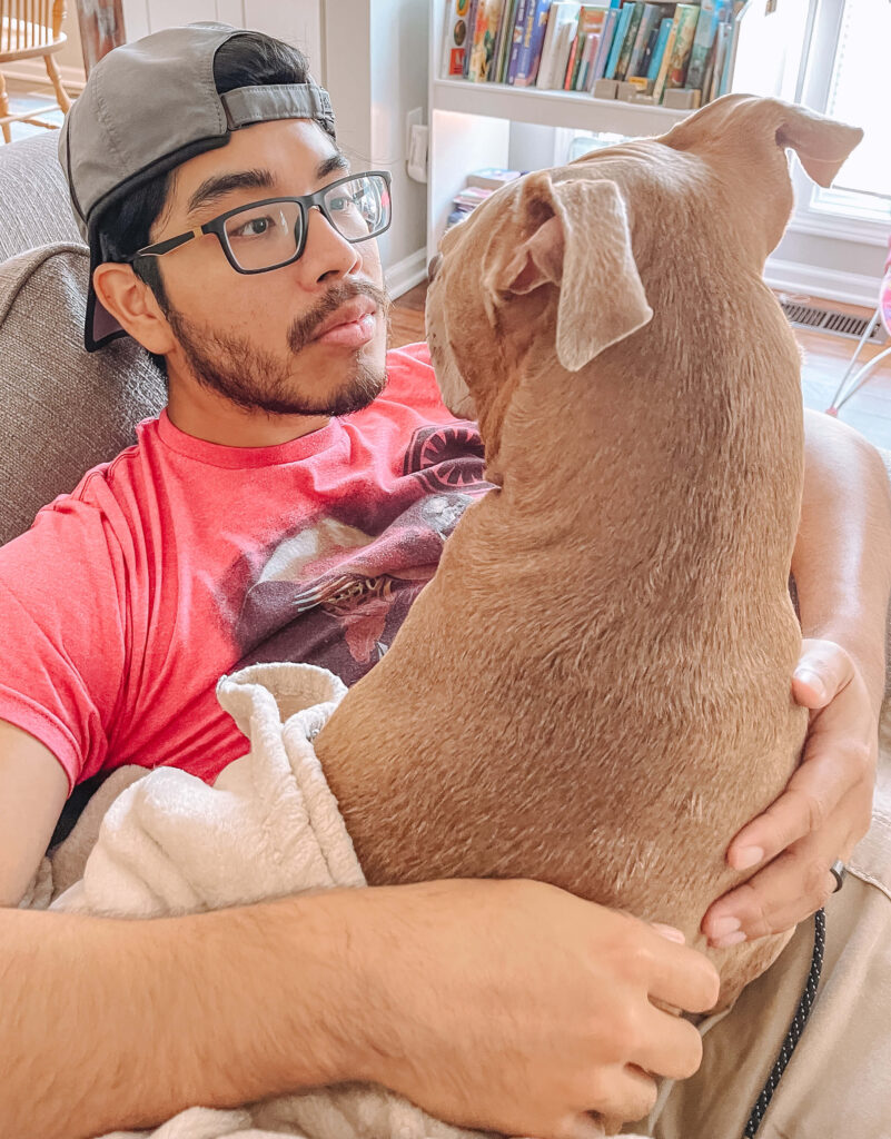 a big tan dog with floppy ears is laying on top of a man's lap and staring at him